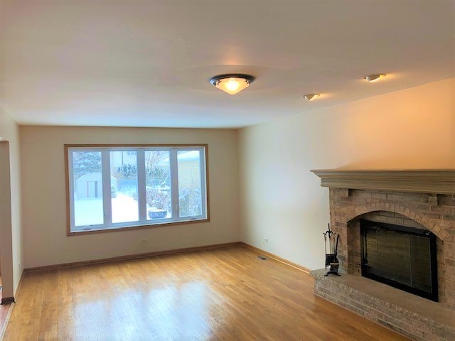 8725 West Sunset Road Niles, IL 60714 - Photo 3 of 15 a view of empty room with wooden floor and fireplace