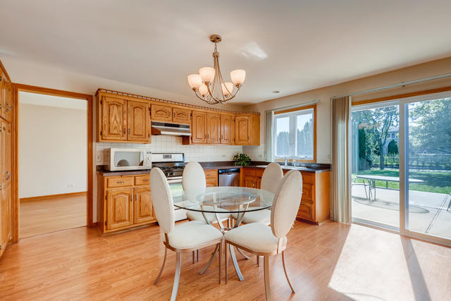 8725 West Sunset Road Niles, IL 60714 - Photo 8 of 15 a dining room with wooden floor a chandelier a glass table and chairs
