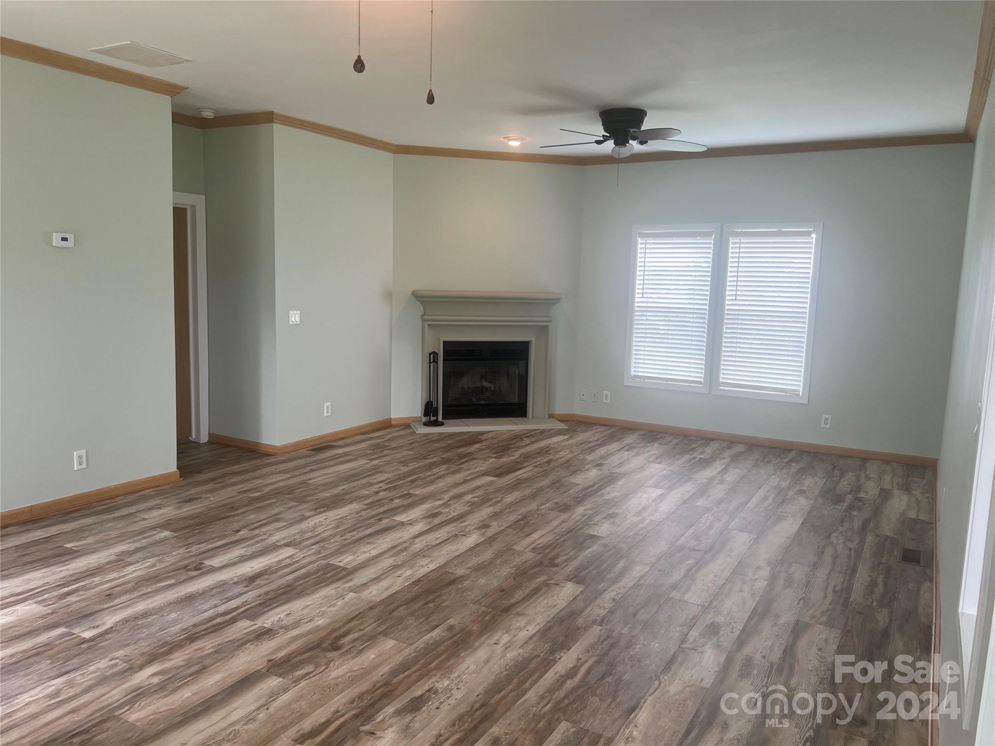 200 Olin Road Olin, NC 28660 - Photo 2 of 17 an empty room with wooden floor fireplace and windows