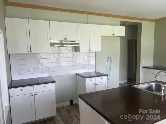 a kitchen with stainless steel appliances granite countertop a sink a stove and white cabinets