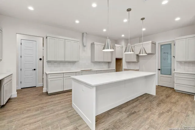 a large white kitchen with kitchen island a sink a stove a refrigerator and white cabinets