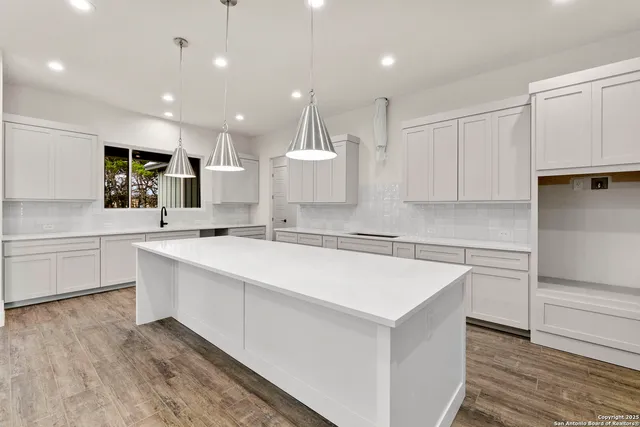 a large white kitchen with kitchen island a sink stainless steel appliances and cabinets