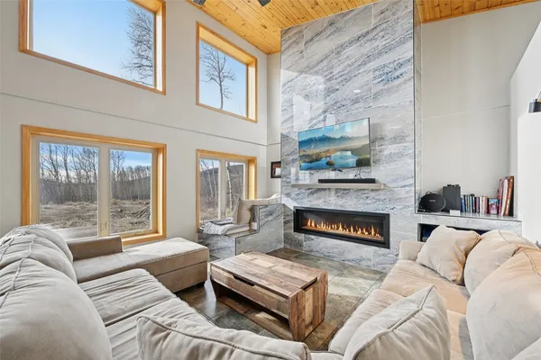 a living room with furniture large windows and a fireplace