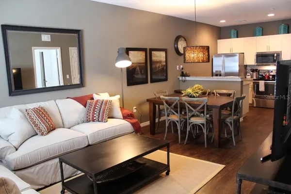 a living room with furniture a rug and kitchen view