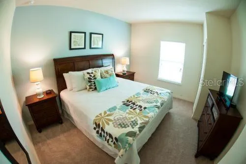 a bedroom with a bed and a flat tv screen on a dresser