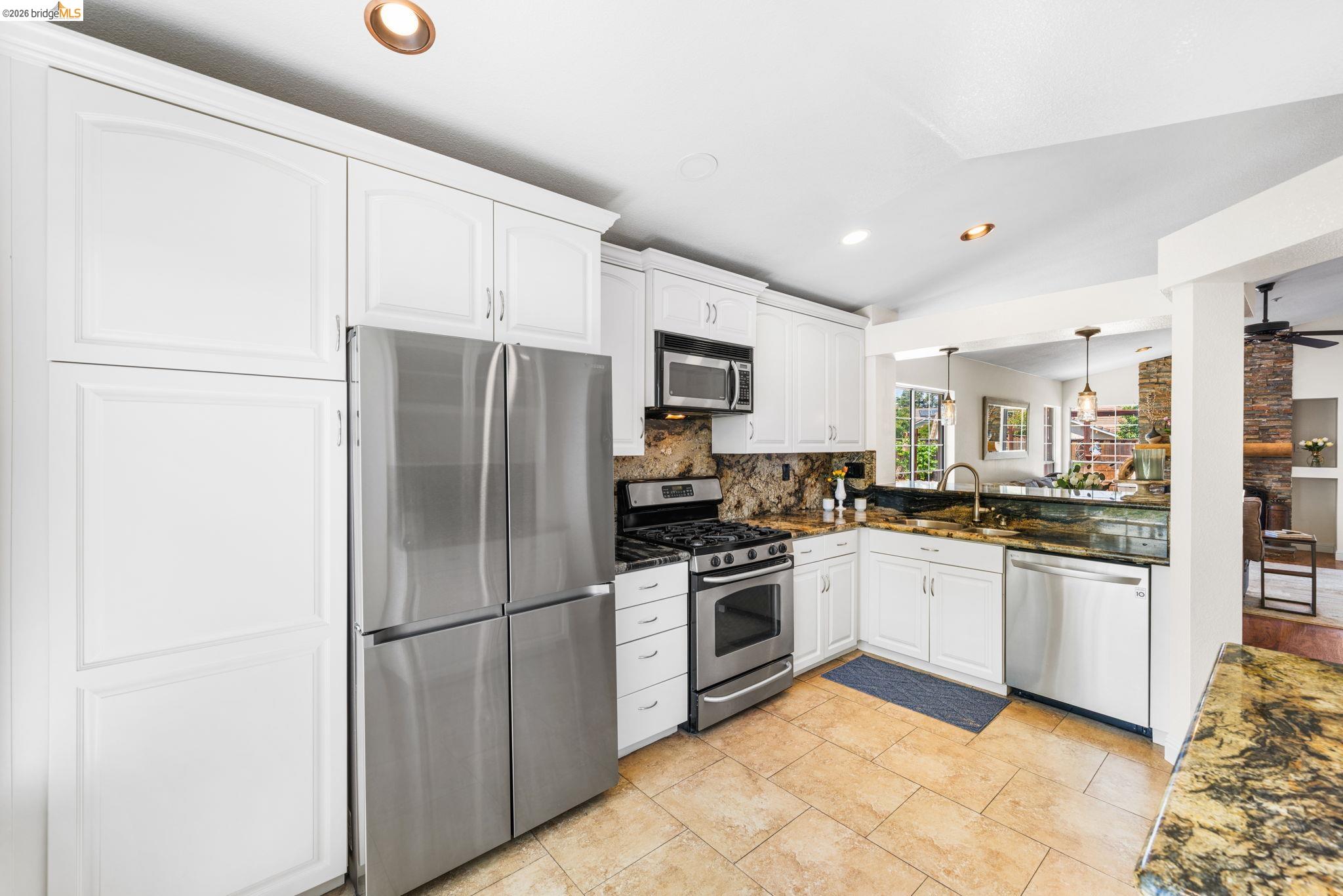 1186 El Rio Court Livermore, CA 94551 - Photo 14 of 60 Modern kitchen featuring white cabinetry, stainless steel appliances, speckled stone countertops, and a coordinating stone backsplash