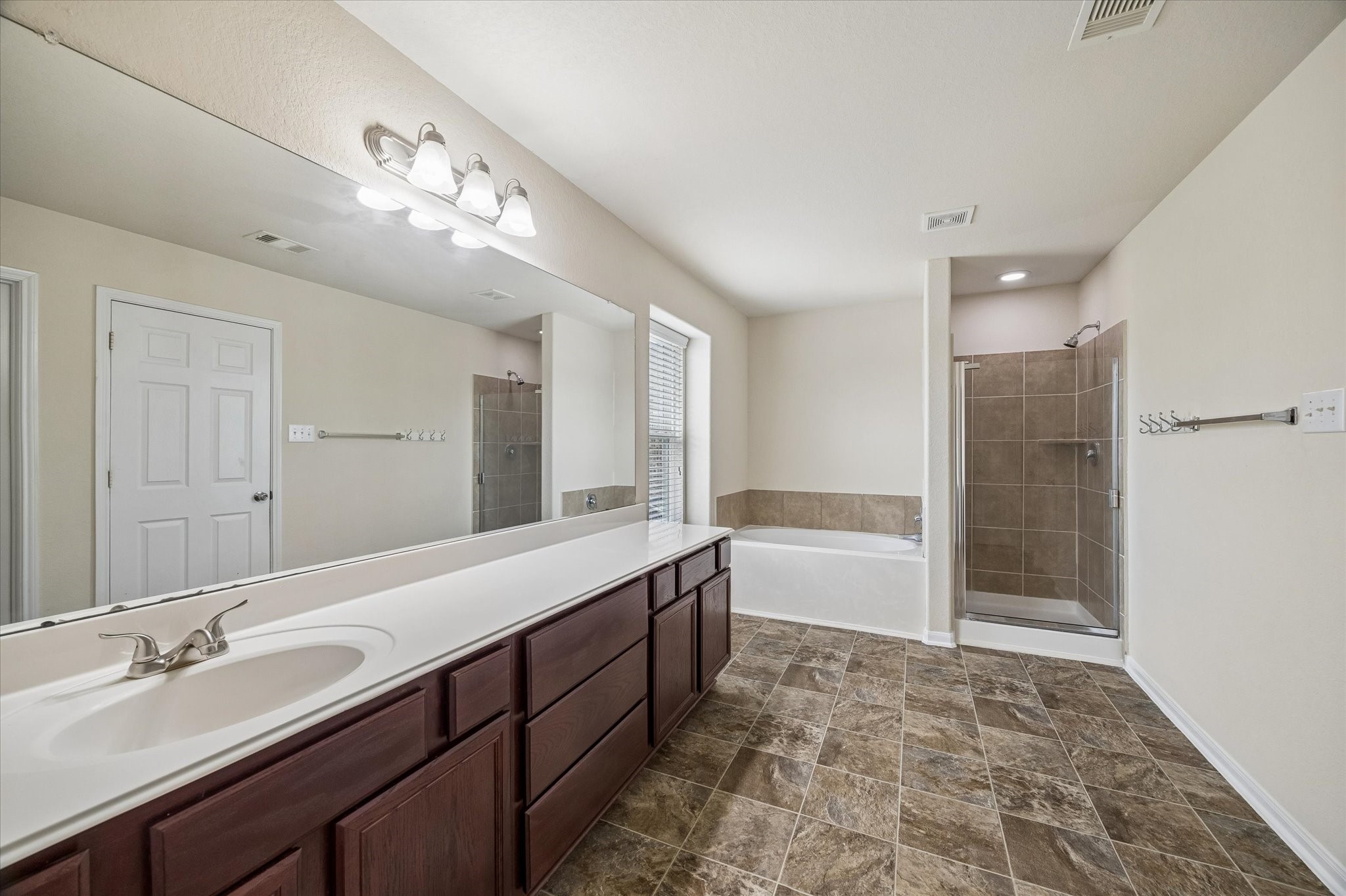 15642 South Fall Fern Circle Houston, TX 77044 - Photo 21 of 32 a spacious bathroom with a bathtub shower sink double vanity and a mirror