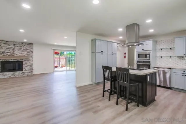 a kitchen with stainless steel appliances granite countertop a kitchen island a stove a table and a refrigerator