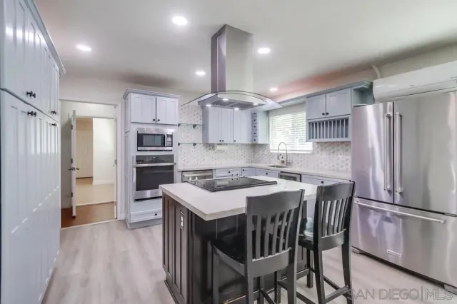 a kitchen with stainless steel appliances a refrigerator a sink dishwasher a stove and white cabinets with wooden floor