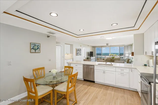 a kitchen with stainless steel appliances granite countertop a sink a stove a refrigerator cabinets and chairs