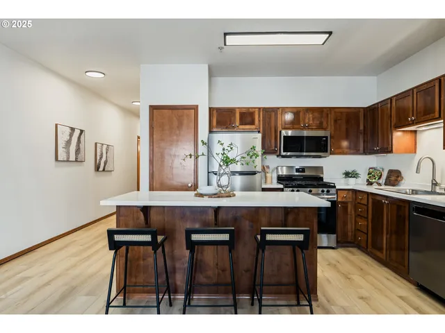 a kitchen with stainless steel appliances a table chairs refrigerator and microwave