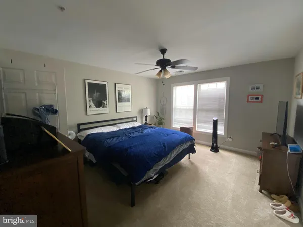 a spacious bedroom with a bed a chandelier and a flat screen tv