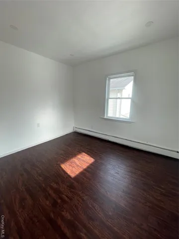 an empty room with wooden floor and window