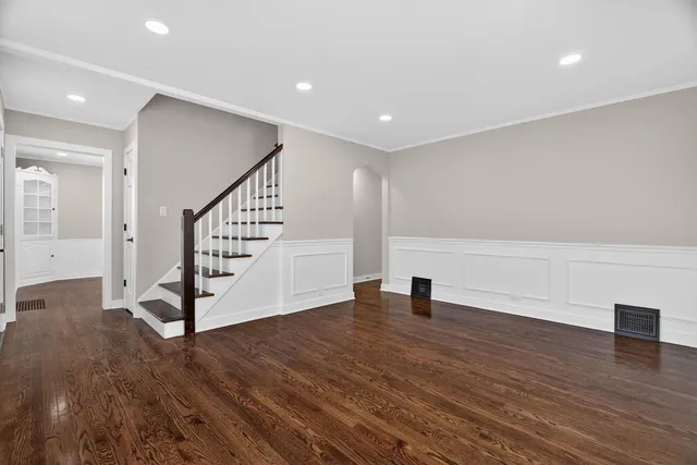 a view of an empty room with wooden floor and stairs