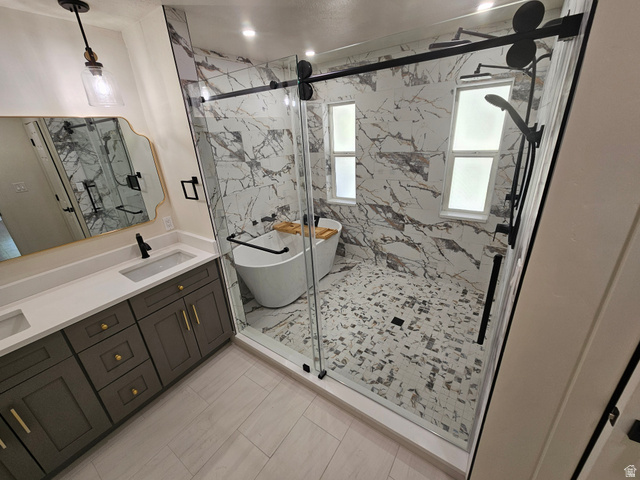 812 East Bates Cyn Road Tooele, UT 84074 - Photo 41 of 144 Bathroom featuring a dual vanity with a light-toned countertop, a frameless glass shower enclosure, a freestanding soaking tub, and a multi-function shower system