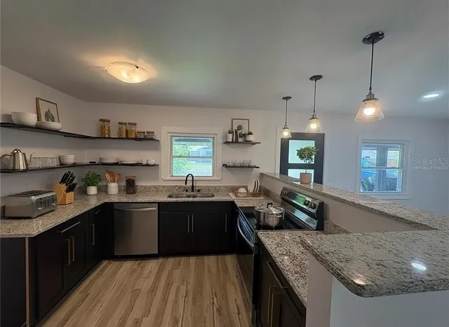 a kitchen with stainless steel appliances granite countertop sink stove and refrigerator