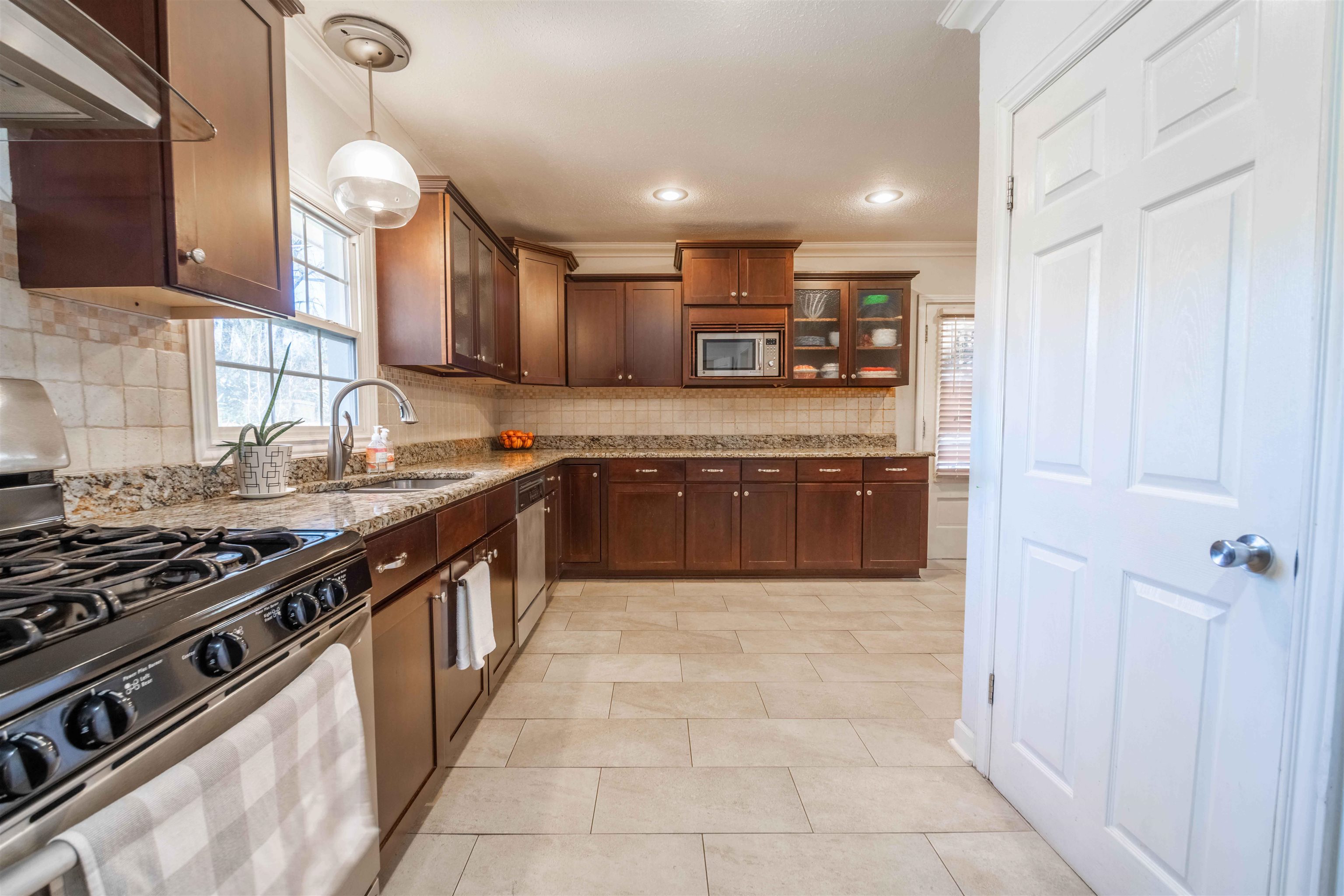 5099 Walnut Grove Road Memphis, TN 38117 - Photo 10 of 24 Kitchen with stainless steel appliances, light stone counters, glass insert cabinets, crown molding, and hanging light fixtures
