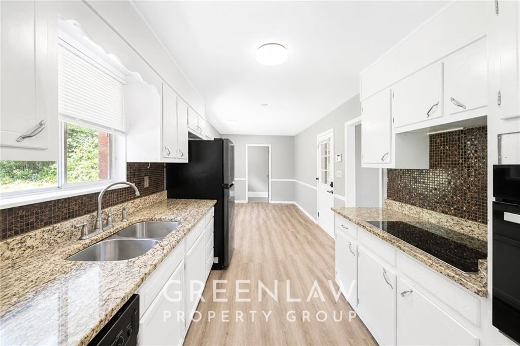 3605 Flat Shoals Road Atlanta, GA 30349 - Photo 12 of 35 a large white kitchen with granite countertop a sink a stove a washer and dryer next to a window