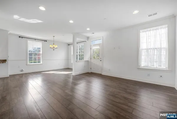 an empty room with wooden floor and windows with curtains view