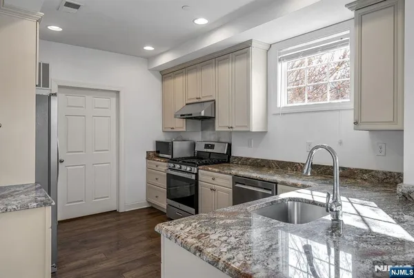 a kitchen with granite countertop a stove a sink and a refrigerator