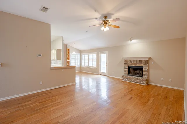 a view of an empty room with window and wooden floor