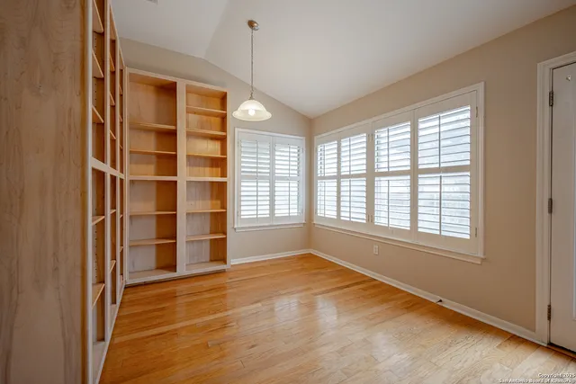 a view of an empty room with a window and wooden floor