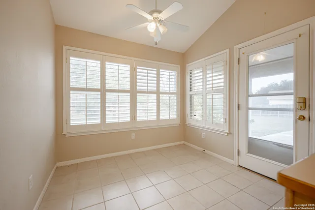 a view of an empty room with a window and a kitchen