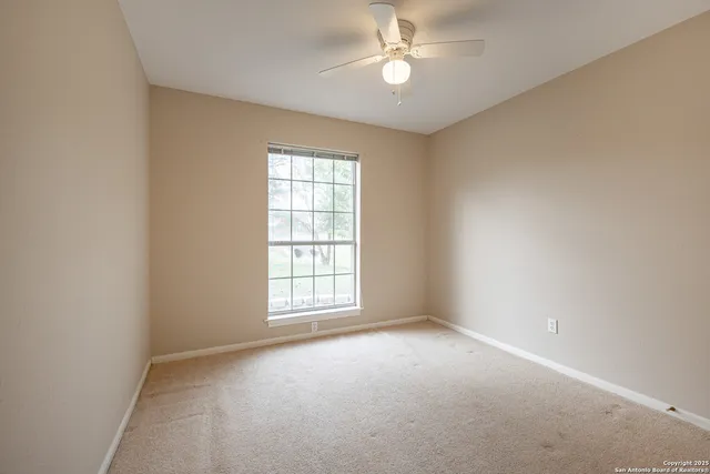an empty room with a window and ceiling fan