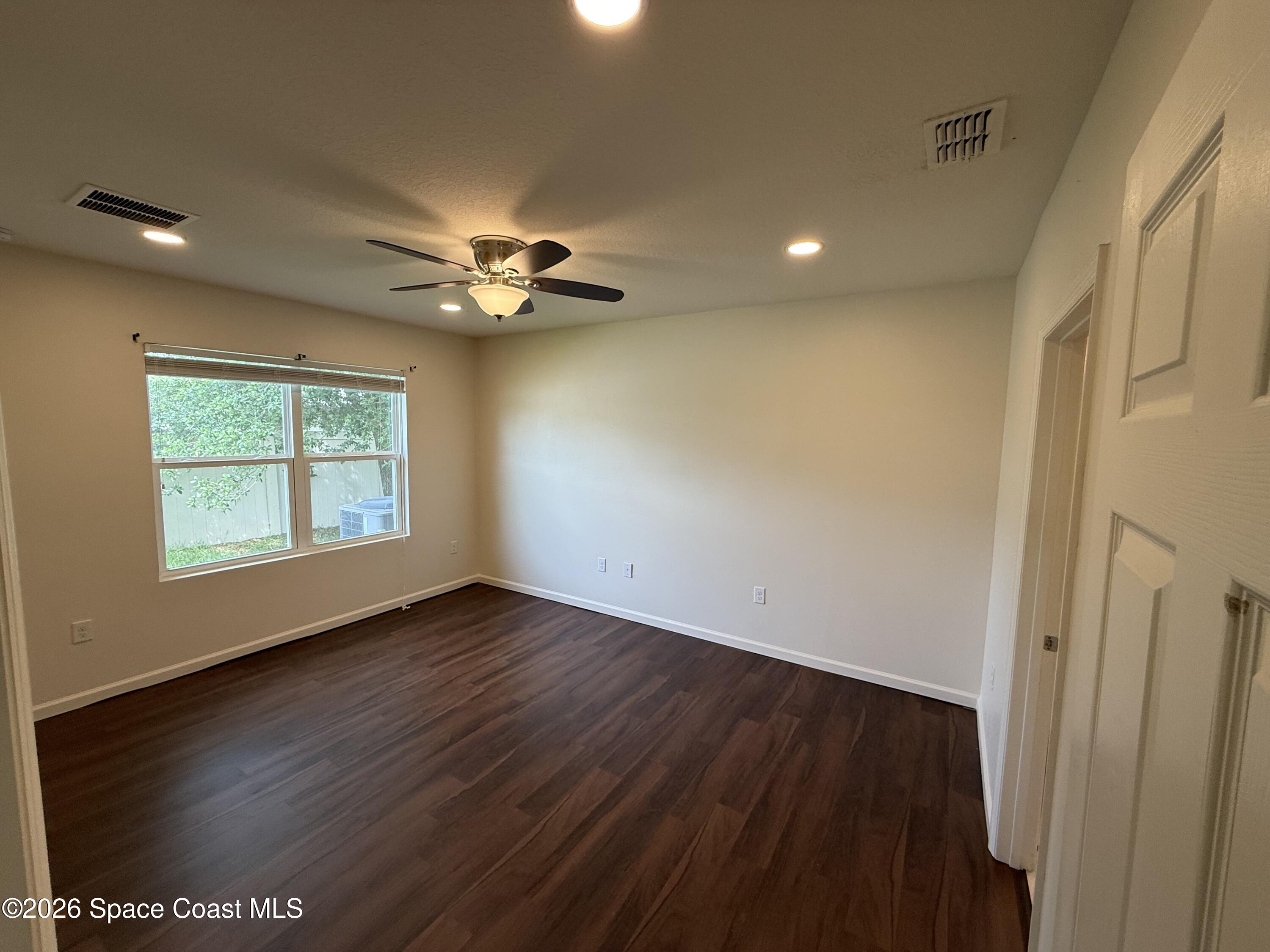 1070 Swiss Pointe Lane Rockledge, FL 32955 - Photo 13 of 18 an empty room with wooden floor and windows