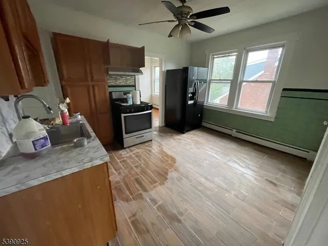 a kitchen with stainless steel appliances granite countertop a stove a sink dishwasher a refrigerator and a stove with wooden floor