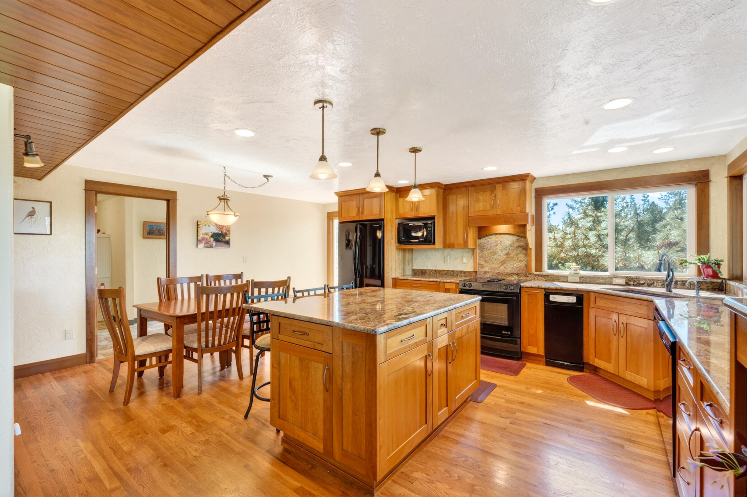 69470 Deer Ridge Road Sisters, OR 97759 - Photo 14 of 96 a kitchen with stainless steel appliances granite countertop a stove top oven a sink dishwasher and a dining table with wooden floor