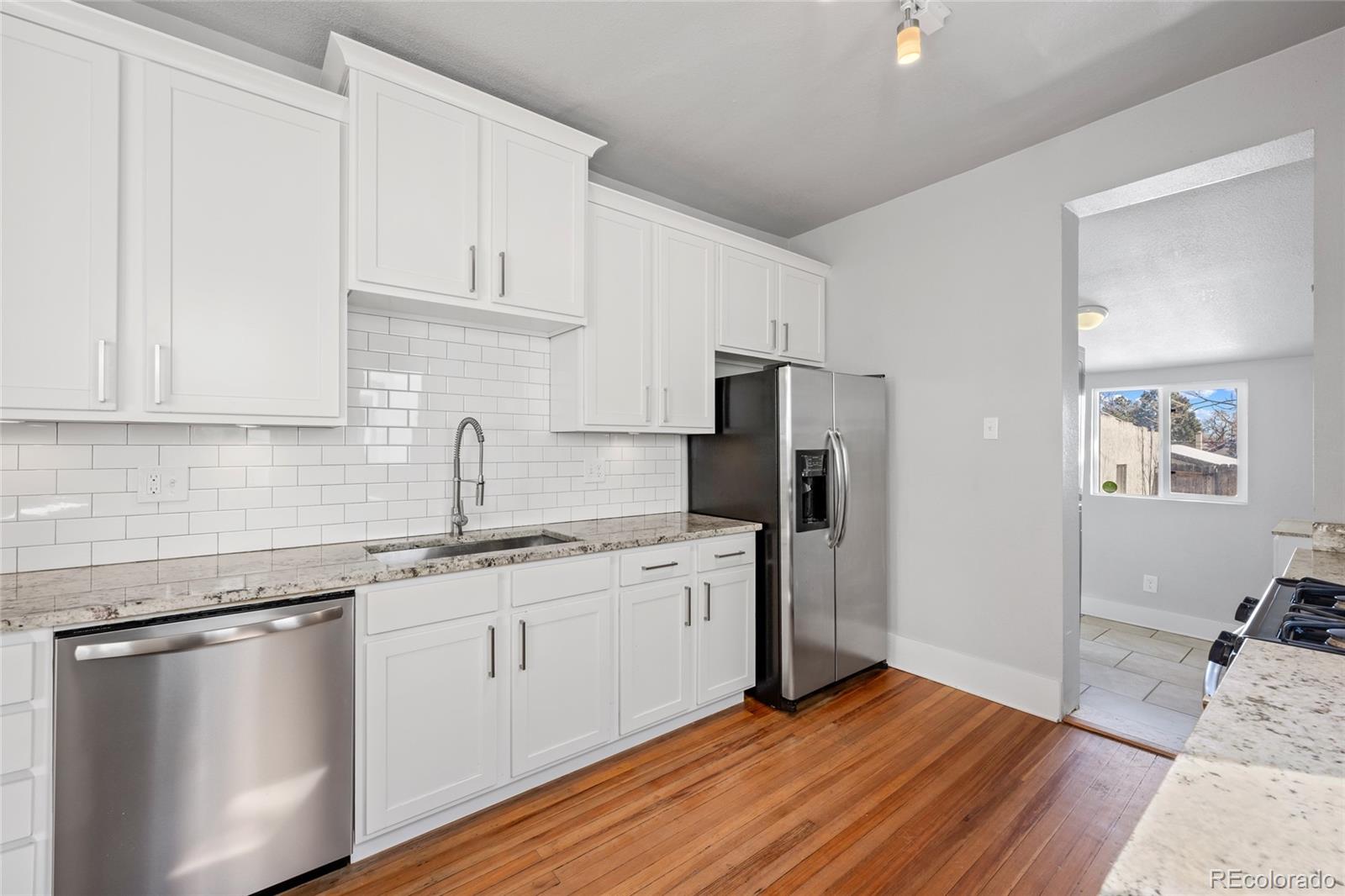 3340 Decatur Street Denver, CO 80211 - Photo 12 of 29 a kitchen with a sink dishwasher a refrigerator and cabinets with wooden floor