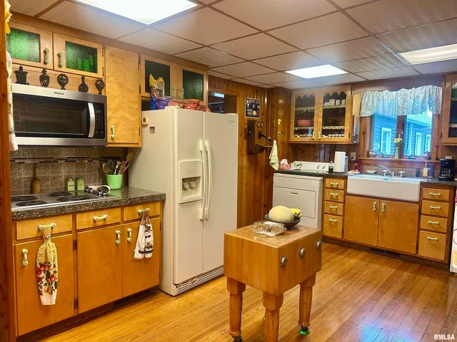 a kitchen with stainless steel appliances granite countertop a refrigerator a stove top oven a sink dishwasher and white cabinets with wooden floor