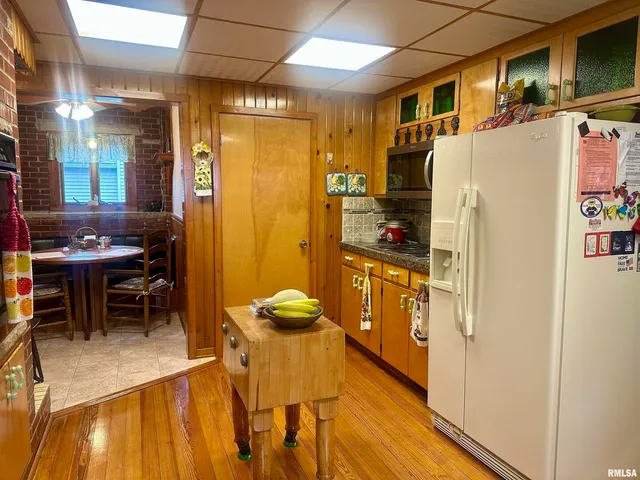 a kitchen with stainless steel appliances a refrigerator a stove a dining table and chairs with wooden floor