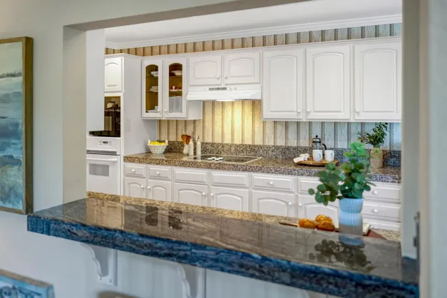 a kitchen with stainless steel appliances granite countertop a sink a stove and white cabinets