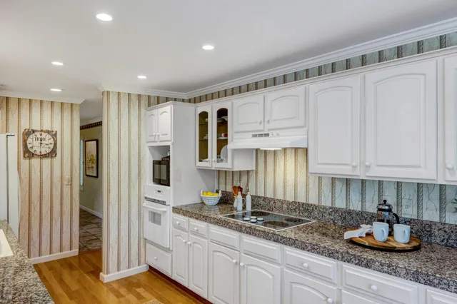 a kitchen with granite countertop white cabinets and stainless steel appliances