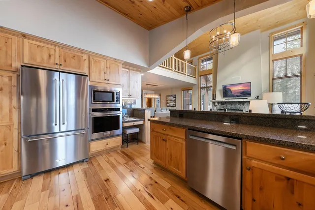 a kitchen with stainless steel appliances wooden floor sink and wooden cabinets