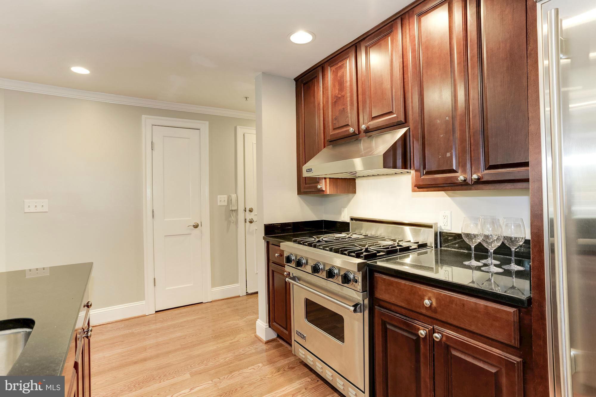 3318 Volta Place Northwest, Unit 2 Washington, DC 20007 - Photo 5 of 30 a kitchen with granite countertop wooden cabinets stainless steel appliances and a wooden floor