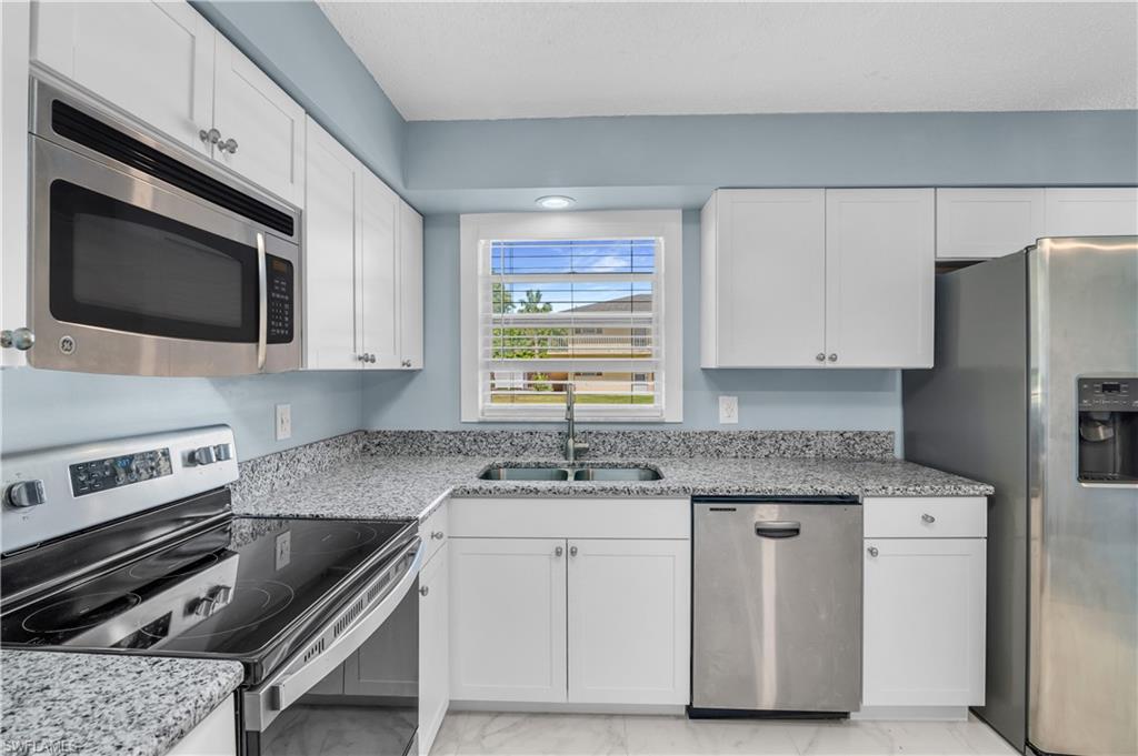 3325 Airport Road North, Unit T1 Naples, FL 34105 - Photo 8 of 19 a kitchen with granite countertop a sink stainless steel appliances and white cabinets