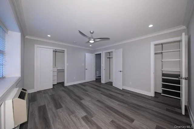a view of an empty room with wooden floor and a ceiling fan