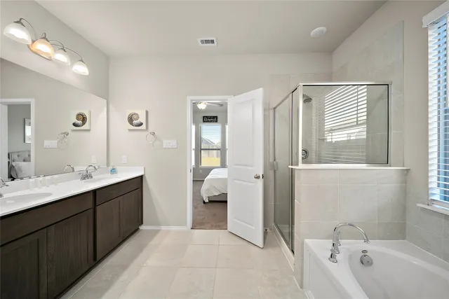 a en suite bathroom with a double vanity sink a mirror and a bathtub