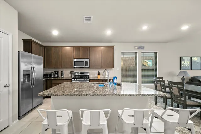 a kitchen with granite countertop a refrigerator and a stove top oven