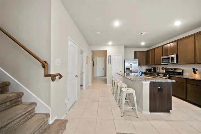 a kitchen with stainless steel appliances granite countertop a refrigerator a sink dishwasher and a stove with wooden floor