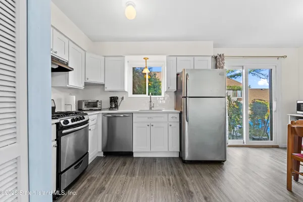 a kitchen with a refrigerator a stove a sink and a wooden floor