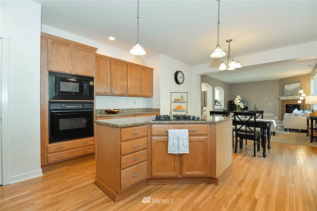 21814 41st Avenue Southeast Bothell, WA 98021 - Photo 15 of 30 a kitchen with stainless steel appliances granite countertop a stove top oven a sink dishwasher a dining table and chairs with wooden floor