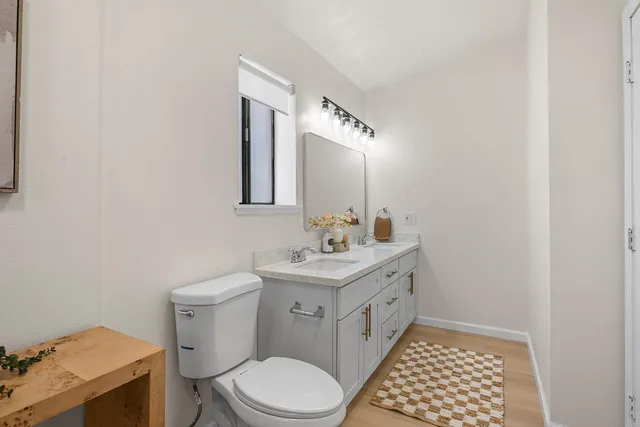 a bathroom with a granite countertop toilet sink and mirror