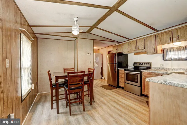 a kitchen with stainless steel appliances kitchen island granite countertop a table chairs and a refrigerator