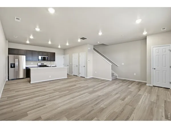 a view of large open kitchen with kitchen island a sink wooden floor and a refrigerator