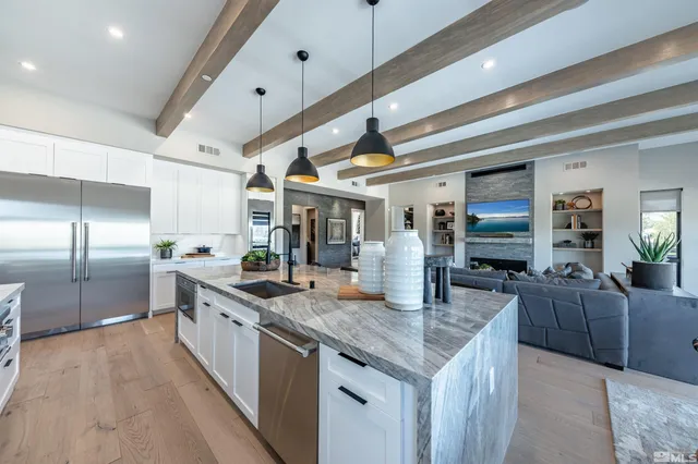 a large kitchen with granite countertop a large counter top and stainless steel appliances