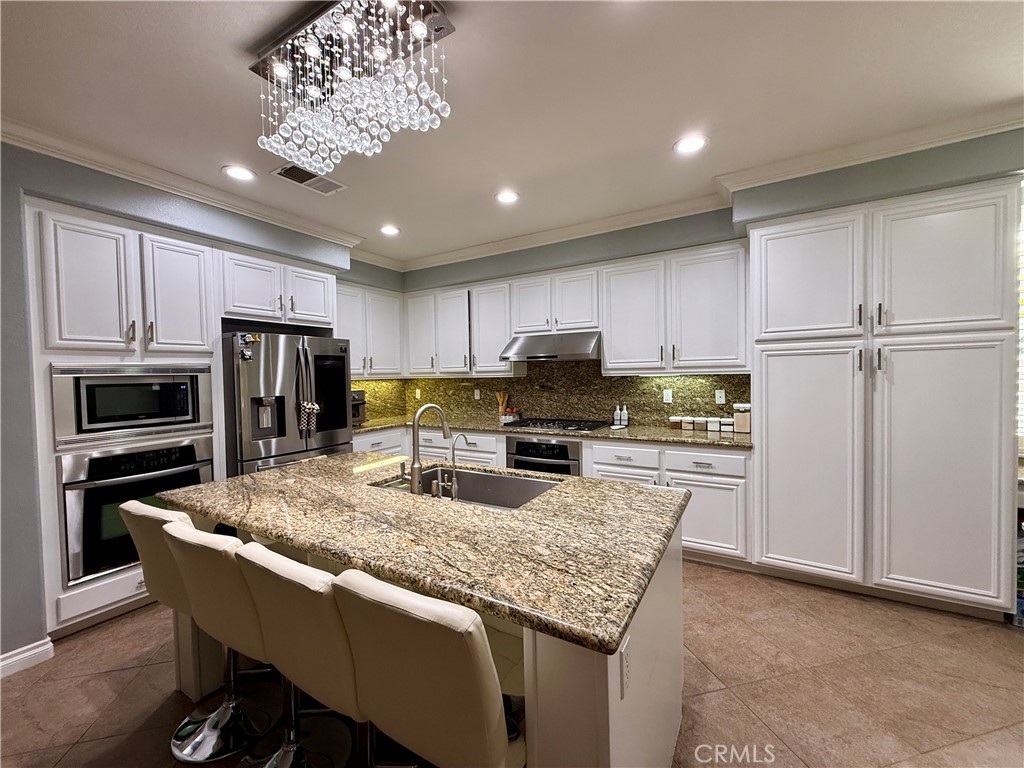 33467 Pitman Lane Menifee, CA 92584 - Photo 13 of 40 a kitchen with kitchen island granite countertop stainless steel appliances and a refrigerator